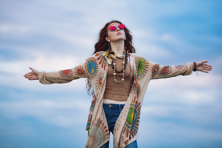 A portrait of a fashion female model against the sky in a coutryside. Contemporary bohemian style. Spirit of freedom. Fashion shot. Bohemian, bo-ho style.の写真素材