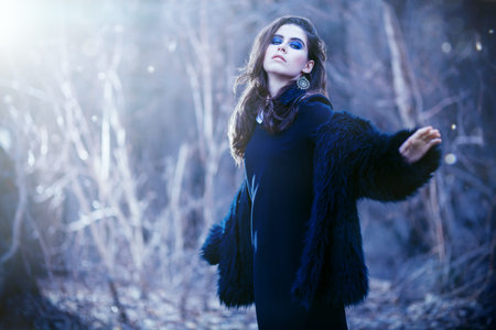 A portrait of a beautiful mysterious girl in black posing in the forest. Beauty, fashion, nature.