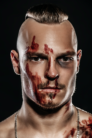 Fight club, MMA. Portrait of a bad guy fighter with a face and body in the blood. Rocker, punk. Close up.の写真素材