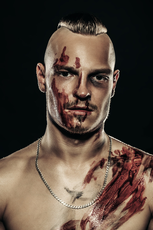 Fight club, MMA. Portrait of a bad guy fighter with a face and body in the blood. Rocker, punk. Close up.の写真素材