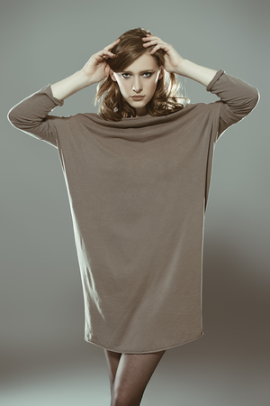 Elegant young woman wearing stylish gray dress. Beauty, fashion concept. Studio shot.の写真素材