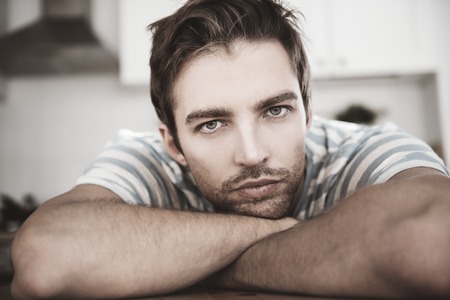 A close up portrait of a handsome dreamy man. Home, casual fashion.の写真素材