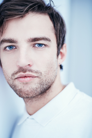 A close up portrait of a handsome man in white over the white background. Beauty, fashion for men.の写真素材