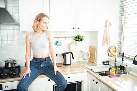 A portrait of a beautiful girl posing in the kitchen. Fashion, interior.の写真素材
