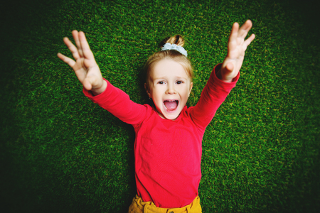A portrait of a cute bright girl posing in the studio over the green grass background. Kids, casual fashion, beauty.の写真素材