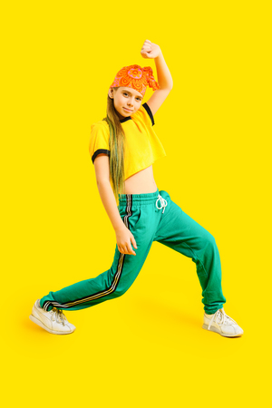 A full length portrait of a young girl posing in the studio over the yellow background. Sport fashion for teenagers.の写真素材