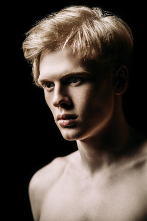 Portrait of a shirtless young man with blond hair posing at studio. Gray background. Men's health.の写真素材