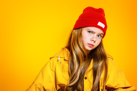 A close-up of a funny girl in bright casual clothes posing in studio. Beauty, fashion for kids.