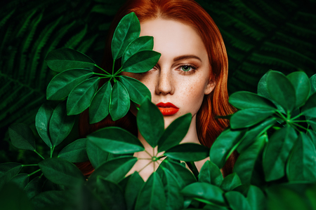 A close up portrait of a lovely mysterious girl with green leaves. Beauty, cosmetics.の写真素材