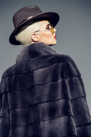 Beautiful woman in luxurious fur coat posing in studio. Luxury, rich lifestyle. Fashion shot.の写真素材