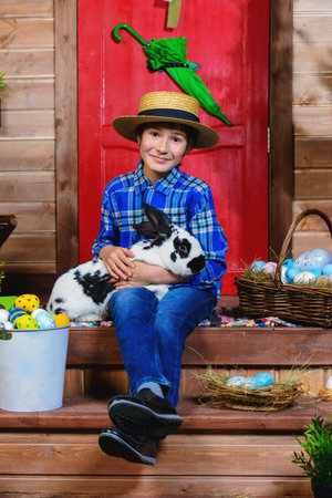 Easter holidays. Happy boy is posing on the porch of a village house. Easter decorations.