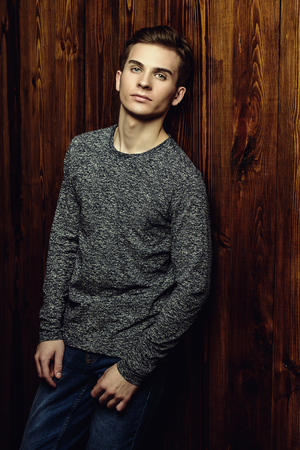 Portrait of a handsome teenage boy over wooden background. Studio shot. Teen fashion.の写真素材