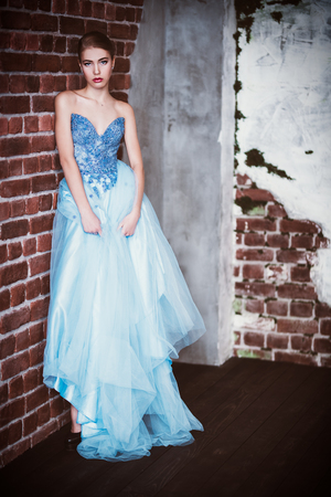 A full length portrait of a charming lady in a fluffy lihjt blue dress posing indoor. Wedding and evening fashion.の写真素材