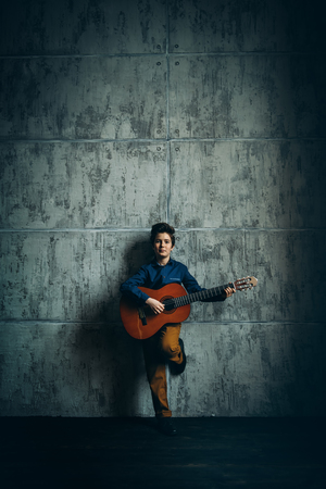 A full length portrait of a young boy posing in the studio with a guitar. Kids, fashion, music, talent.の写真素材