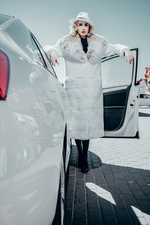 A full length portrait of a gorgeous blonde lady posing near a car. Car, fashion, beauty, chick.の写真素材