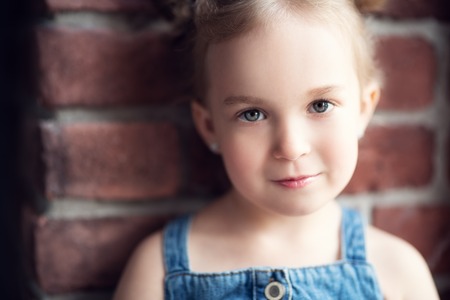 A close up portrait of a pretty girl posing indoor over the brick walll. Kids, beauty.の写真素材