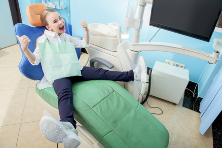 A portrait of a child girl in the cabinet of a dentist. Treatmeat, medicine, hospital.の写真素材