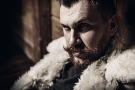 A close up portrait of a brutal mature man posing at the wooden house. Man, beauty.の写真素材