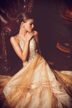 A portrait of a mysterious lady in a beaige dress posing indoor. Fairy tale, beauty, fashion.の写真素材