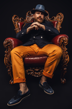A full length portrait of a stylish modern man posing in the armchair. Men fashion, style.の写真素材