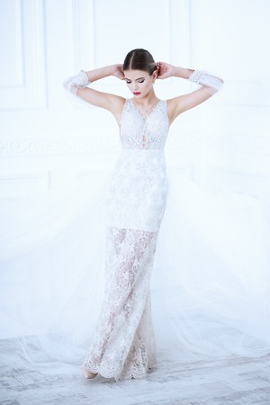 A full length portrait of a charming lady in a wedding dress posing indoor. Wedding fashion, bride.の写真素材
