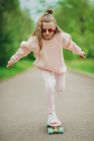 A full length portrait of an active teenager girl posing on the road with a skateboard. Casual kids fashion, active lifestyle.の写真素材