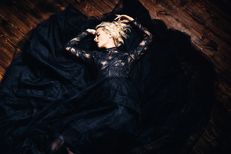 A beautiful blonde lady is lying on the floor. Evening dress. Fashion, beauty.の写真素材
