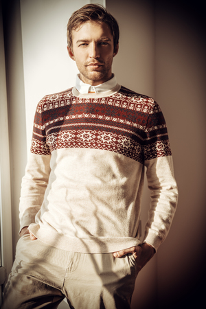 A portrait of a handsome man at the window. Spring fashion for men, interior.の写真素材