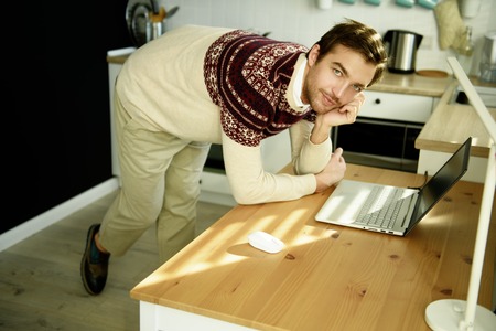 A portrait of a man at home with a laptop. Casual spring fashion, gadgets for men.の写真素材