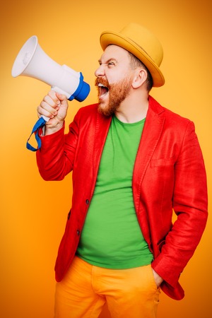 A portrait of a bright man posing in the studio with a mouthpiece over the yellow background. Men, beauty, colors, fashion.の写真素材