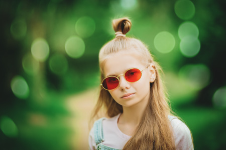 A close up portrait of a beautiful teenager girl posing in the field. Kids, nature, summer casual fashion, beauty.の写真素材