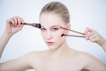 Portrait of a beautiful young woman with brushes. Beauty, cosmetics makeup.の写真素材