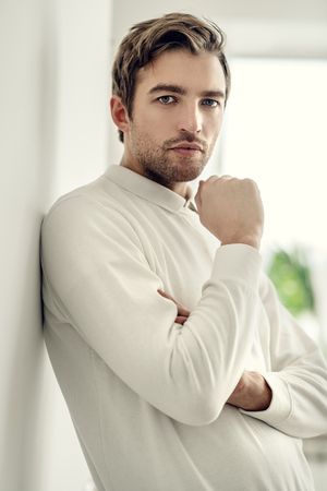 A portrait of a handsome man in white over the white room. Beauty, fashion for men.の写真素材