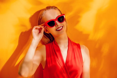 A portrait of a cheerful young lady posing in sunglasses over the background with shadows of palms. Summer, beauty.の写真素材
