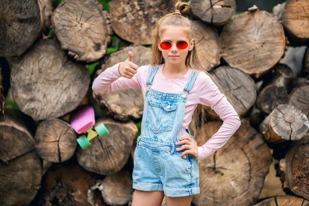 A portrait of an active teenager girl posing with a skateboard. Casual kids fashion, active lifestyle.の写真素材