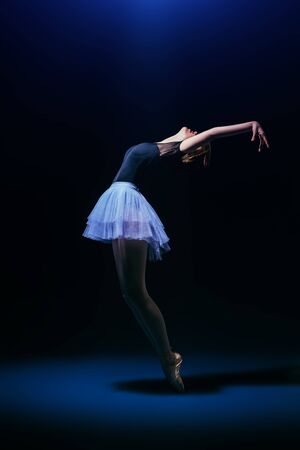 A full length portrait of an elegant refined ballet female dancer posing in the studio over the black background. Talent, fashion for ballet dancers.の写真素材