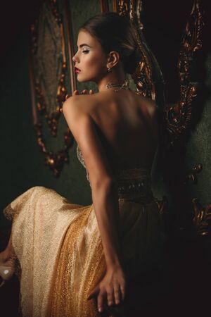 A portrait of a mysterious lady in a beige dress posing indoor. Fairy tale, beauty, fashion.の写真素材