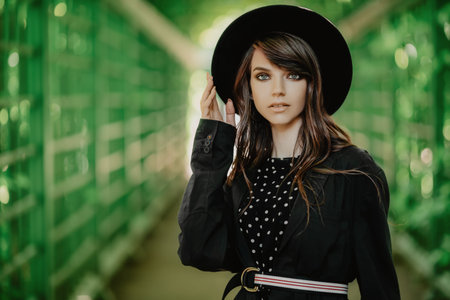 A portrait of a young fashionable woman wearing a hat walking in the park. Beauty, fashion.