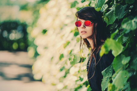 A portrait of a young fashionable woman in the park. Beauty, fashion, optics.