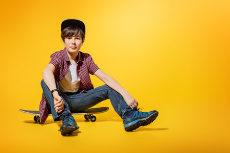 A full length portrait of a bright young boy posing in the studio over the yellow background with a...