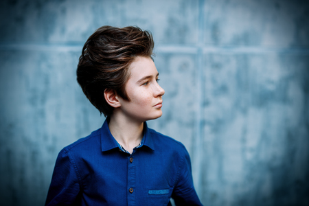 A portrait of a young boy posing near the grey wall. Kids, beauty, fashion, casual style.の写真素材