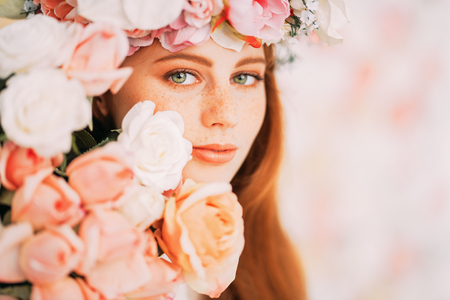A close up portrait of a lovely beautiful girl with a wreath of flowers on the head on a floral background. Beauty, cosmetics.の写真素材
