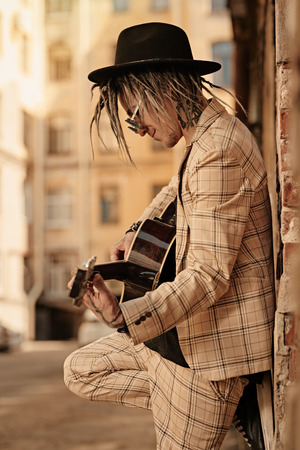 A portrait of a young guitarist in the street. Casual summer fashion, music.の写真素材