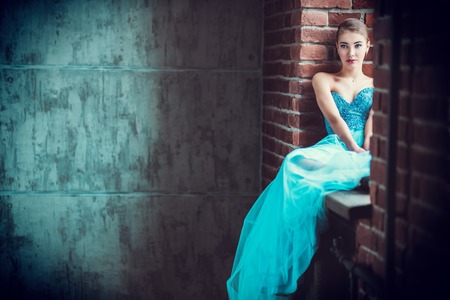 A portrait of a mysterious lady in a fluffy dress posing indoor on the windowsill. Fairy tale, fashion.の写真素材