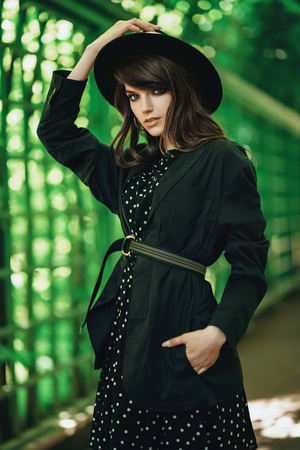 A portrait of a young fashionable woman wearing a hat walking in the park. Beauty, fashion.の写真素材