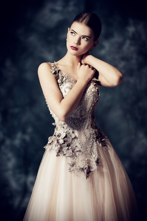 A portrait of a mysterious lady in a light beige dress posing indoor. Fairy tale, beauty, fashion.の写真素材