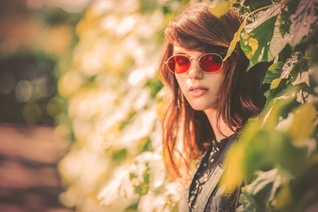 A portrait of a young fashionable woman in the park. Beauty, fashion, optics.の写真素材