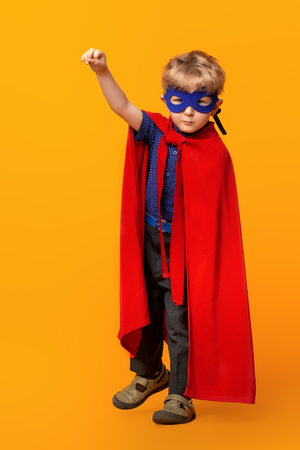 A full length portrait of a funny serious young boy posing in the costume of superhero. Kids development and education concept.の写真素材