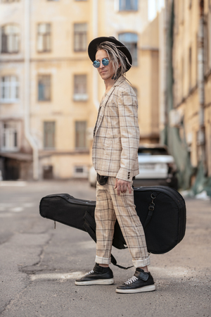 A full length portrait of a young guitarist in the street. Casual summer fashion, music.の写真素材