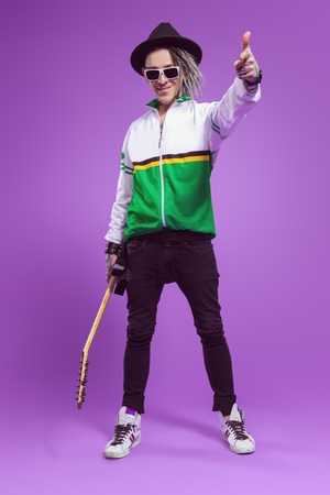 A full length portrait of a cool young guitarist in the studio. Casual punk fashion, music.の写真素材